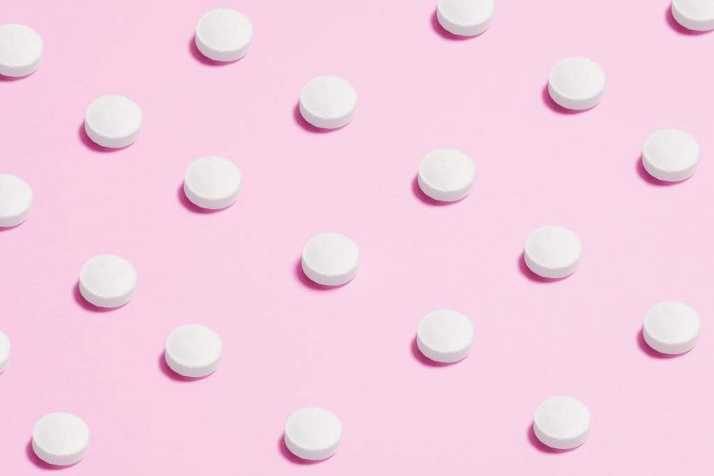 White Round Capsule on Pink Background Close-up Photography