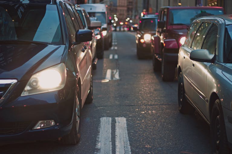 A congested city street lined with cars stuck in traffic at dusk, showcasing urban life.