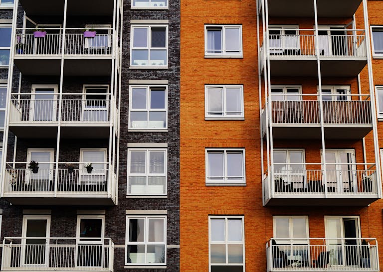 Detailed view of a modern apartment building's exterior with balconies and glass windows.