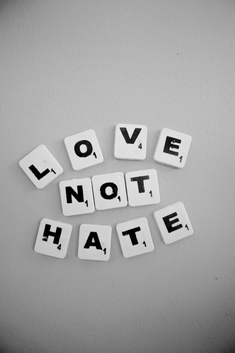 Black and white Scrabble tiles spelling 'LOVE NOT HATE' on a flat surface.