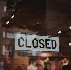 Classic closed sign hanging in front of a store window.