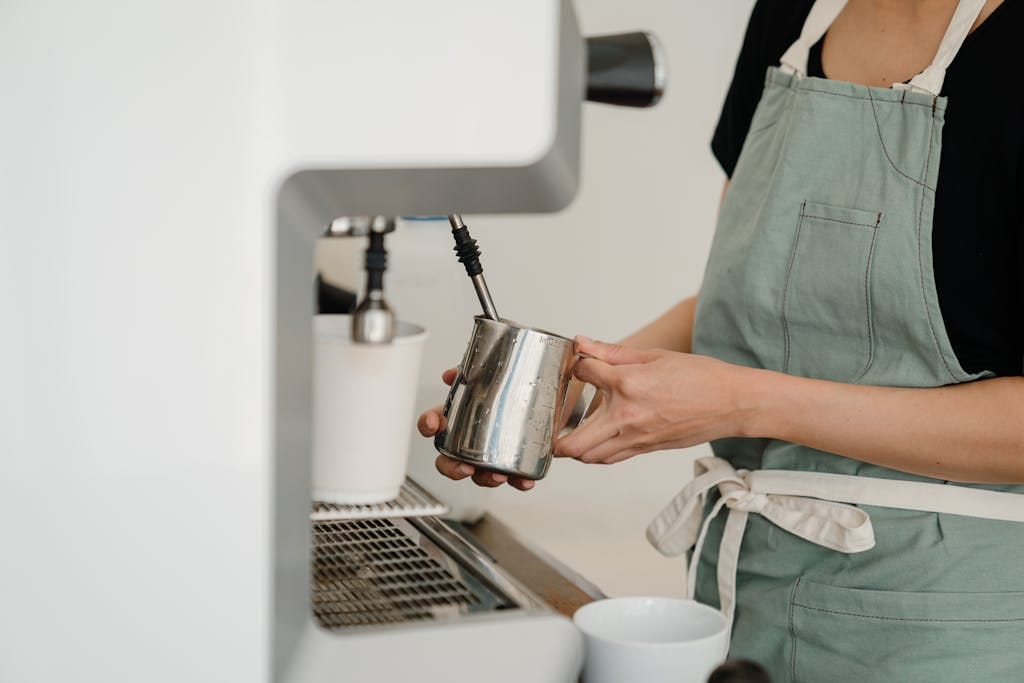 A barista in an apron prepares fresh espresso in a modern café setting.
