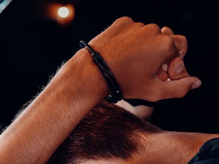 A close-up of a hand in handcuffs against a dark background, depicting a concept of security and restraint.