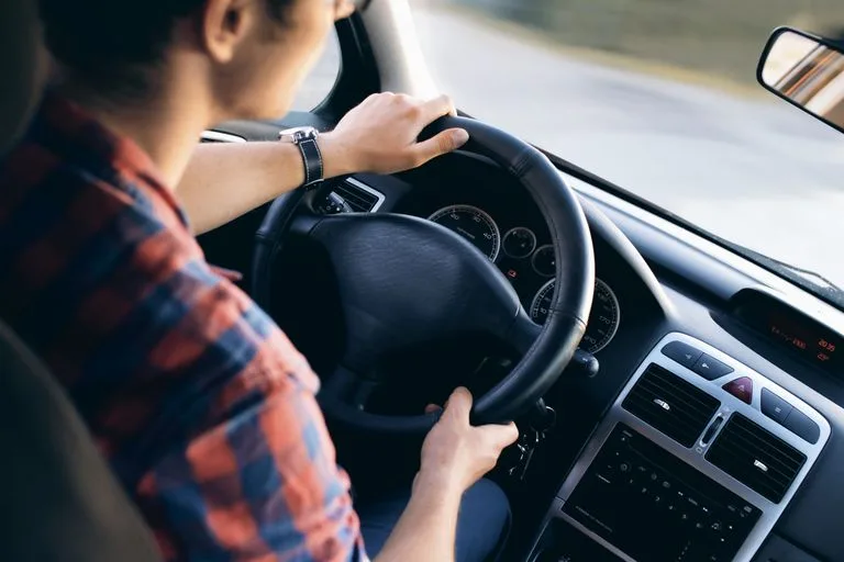 Close-up view of a man driving a modern car, showing dashboard and steering details. Flat lay of cannabis leaf and 'MEDICINE' spelled with Scrabble tiles on white background. Medicinal Cannabis and Driving.